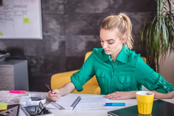 A digital marketing strategist planning an SEO campaign and taking notes at her desk